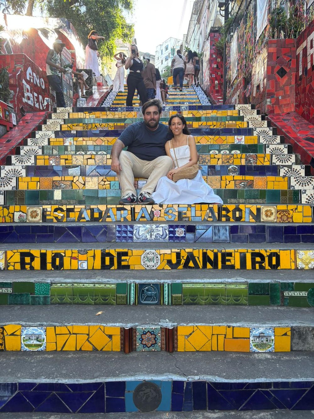 Cláudia e Rafael sentados na Escadaria Selarón, no Rio de Janeiro